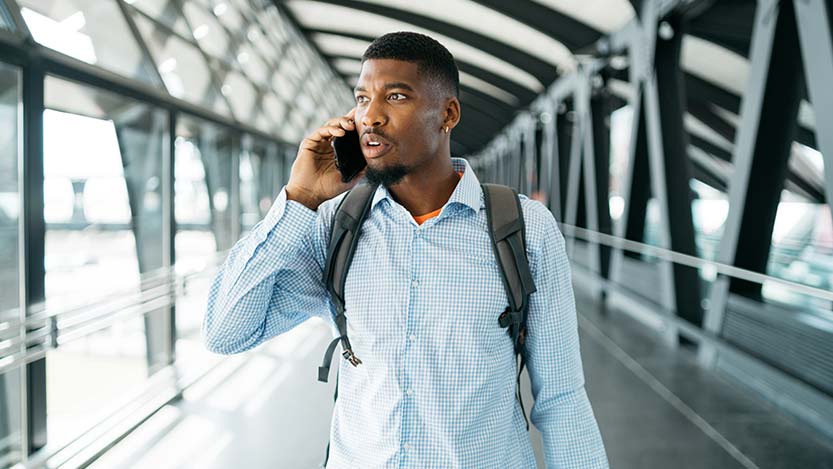 A man inside a building talks on the phone while looking away from the camera.