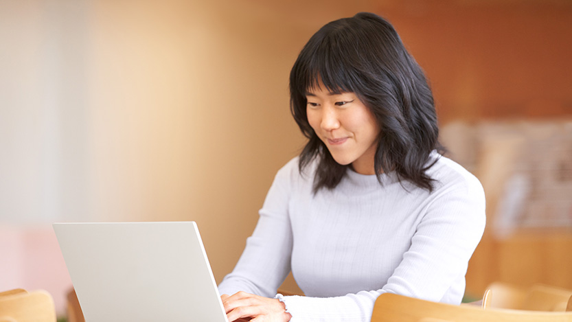 A woman smiling while working on her laptop computer.